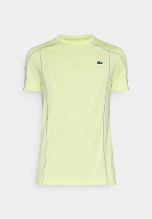 T-shirt atletico a maniche corte in giallo brillante con cuciture blu e logo Lacoste sul lato sinistro del petto. Materiale morbido e sintetico.