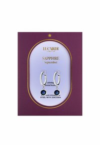 Premium roestvrijstalen oorbellen met een zilveren hoepelontwerp, met hangende blauwe zirconia stenen op een paarse kaartachtergrond.