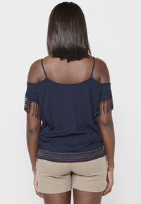 Merev sinise v�ärvi off-shoulder top koos pitsist äärtega varrukatel ja sakilise tikandiga allääres, kombineeritud beežide lühikeste pükstega. Sile kanga tekstuur.