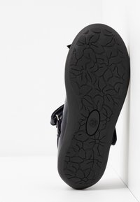 Czarna sandał z teksturowaną gumową podeszwą z kwiatowym wzorem. Regulowany pasek i błyszczący materiał na cholewce.