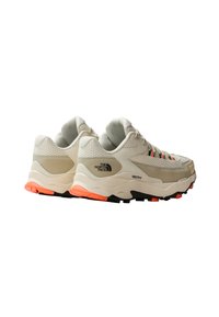 Zapatillas de running beige con una parte superior texturizada, acentos naranjas y suelas negras. Presentan un logo en el lateral y una suela acolchada para mayor soporte.