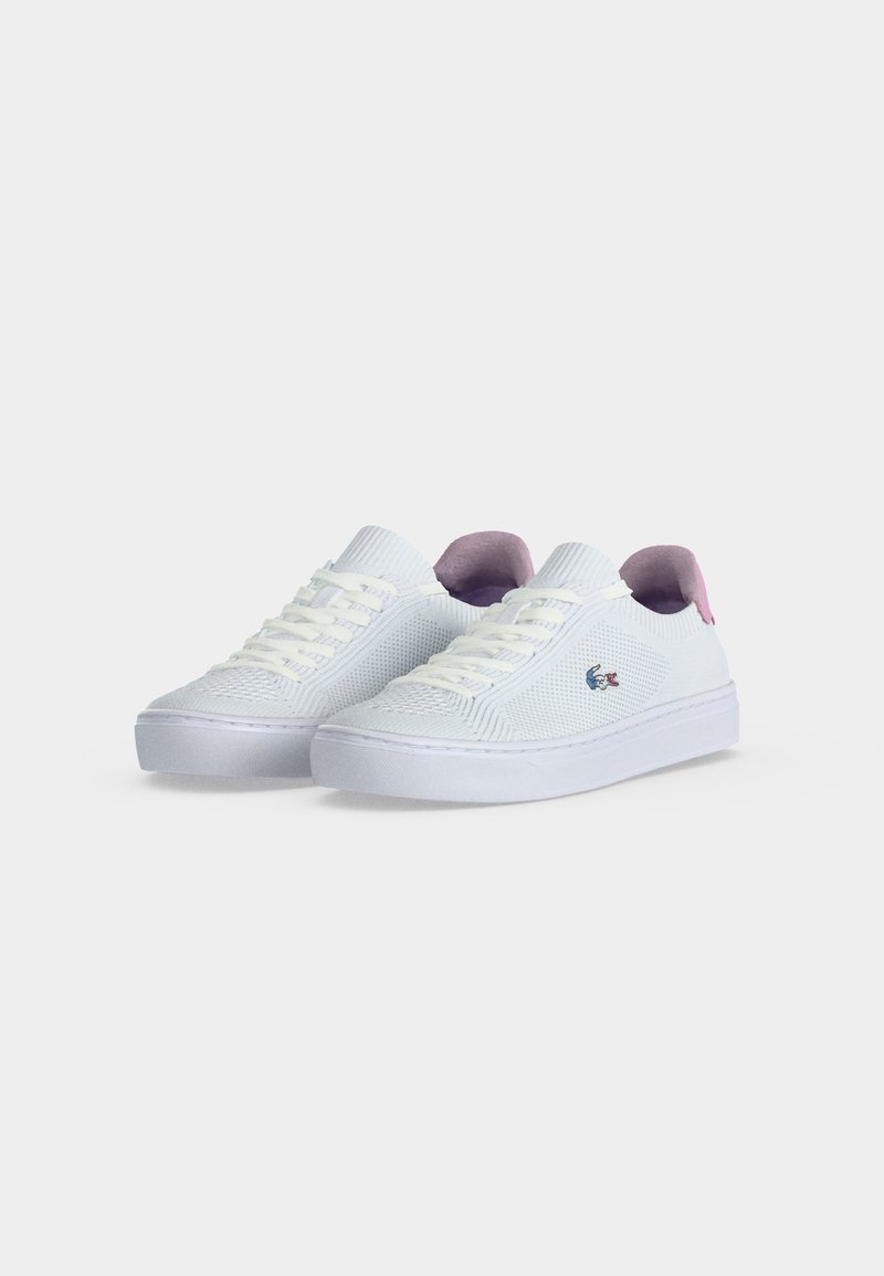 Weiße flache Sneaker mit Strickstruktur, weißen Schnürsenkeln, rosa Fersenlaschen und einem kleinen gestickten Logo an der Seite.