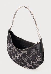 Sac à bandoulière noir avec une bandoulière en chaîne, présentant un motif de lunettes blanches. Tissu texturé et fermeture éclair avec poche intérieure.