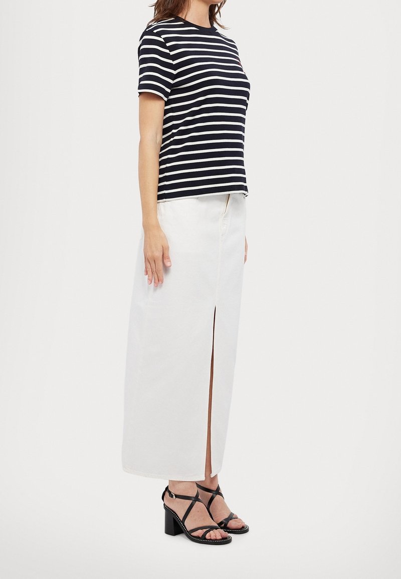 Námořnické a bílé pruhované tričko s krátkým rukávem; bílé maxisukně s předním rozparkem; černé sandály na podpatku s překříženými pásky.