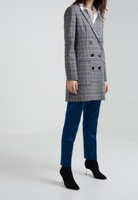 Gray plaid double-breasted blazer with black buttons, paired with blue slim-fit trousers and black sock booties with pointed toes.