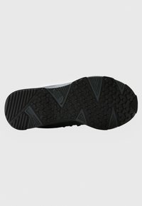 Sole di scarpa sportiva nera con un motivo testurizzato, caratterizzata da scanalature angolari e impugnature esagonali per una maggiore aderenza. Materiale sintetico leggero.