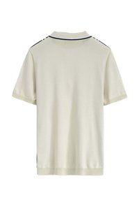 Polo dans un tissu crème clair avec des manches courtes. Accents bleu marine le long du col et des épaules. Texture douce et lisse.