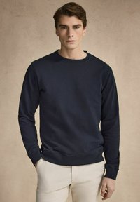 Mörkblå sweatshirt i bomullsblandning, med rund halsringning, långa ärmar och ribbade muddar och nederkant. Slät yta, minimalistisk design.