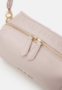 Borsa in pelle texturizzata rosa con hardware dorato, dotata di chiusura con zip superiore e logo incastonato. Include doppie zip e tracolla a catena.