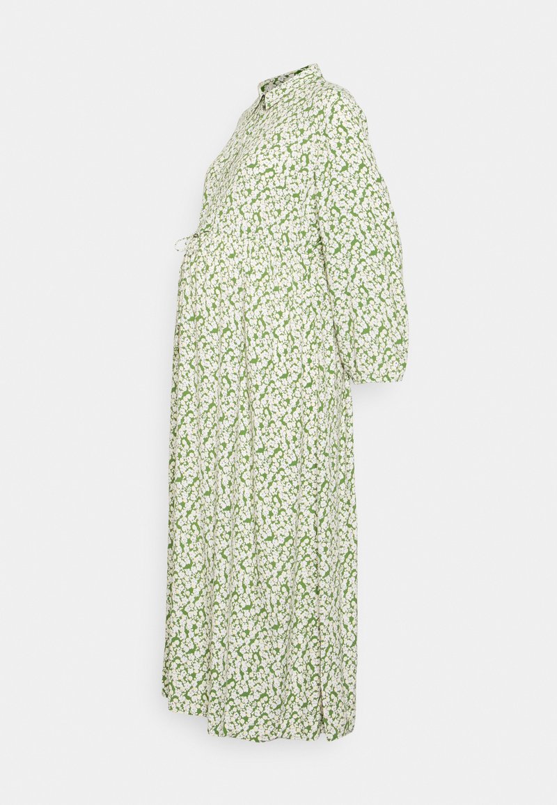 Vestido floral verde com colarinho abotoado, mangas largas bufantes e cintura franzida. Apresenta flores brancas sobre um fundo verde. Comprimento longo.