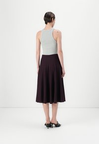 Un débardeur gris à côtes associé à une jupe évasée violet foncé, tous deux présentant une texture lisse et un design simple et fluide.