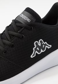 Zwarte mesh sneaker met bijpassende veters, met Kappa-logo op de tong en wit logo aan de zijkant. Lichtgewicht ontwerp en rubberen zool.