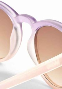 Paars doorzichtige zonnebril met een verloop van bruine glazen en lichtroze pootjes, met een gladde textuur en gebogen ontwerp.