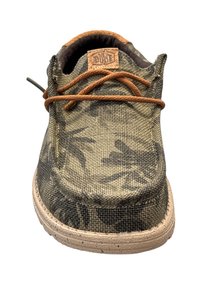 Scarpa slip-on in tela verde oliva con motivo camo, lacci marroni, tomaia in tessuto e suola in gomma beige con dettagli testurizzati.