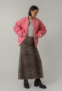 Rosa puffjacka, lättvikts med dragkedja fram, tillsammans med en maxikjol med leopardmönster. Svarta ankellånga stövlar fulländar looken.