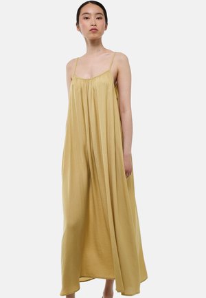 Robe maxi en tissu jaune doux, dotée de fines bretelles, d'un corsage froncé et d'une silhouette fluide atteignant les chevilles.