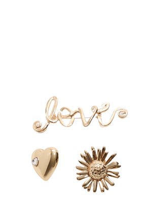 Tre guld accessories: en kursiv "kærlighed" skrift, et glinsende hjerte med en rhinsten, og en tusindfryd med teksturerede kronblade.