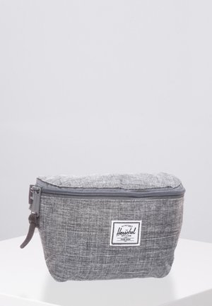 Grauer Stoff-Herschel-Reißverschlussbeutel mit strukturiertem Muster und einem weißen rechteckigen Markenschild auf der Vorderseite, auf einer weißen Oberfläche platziert.