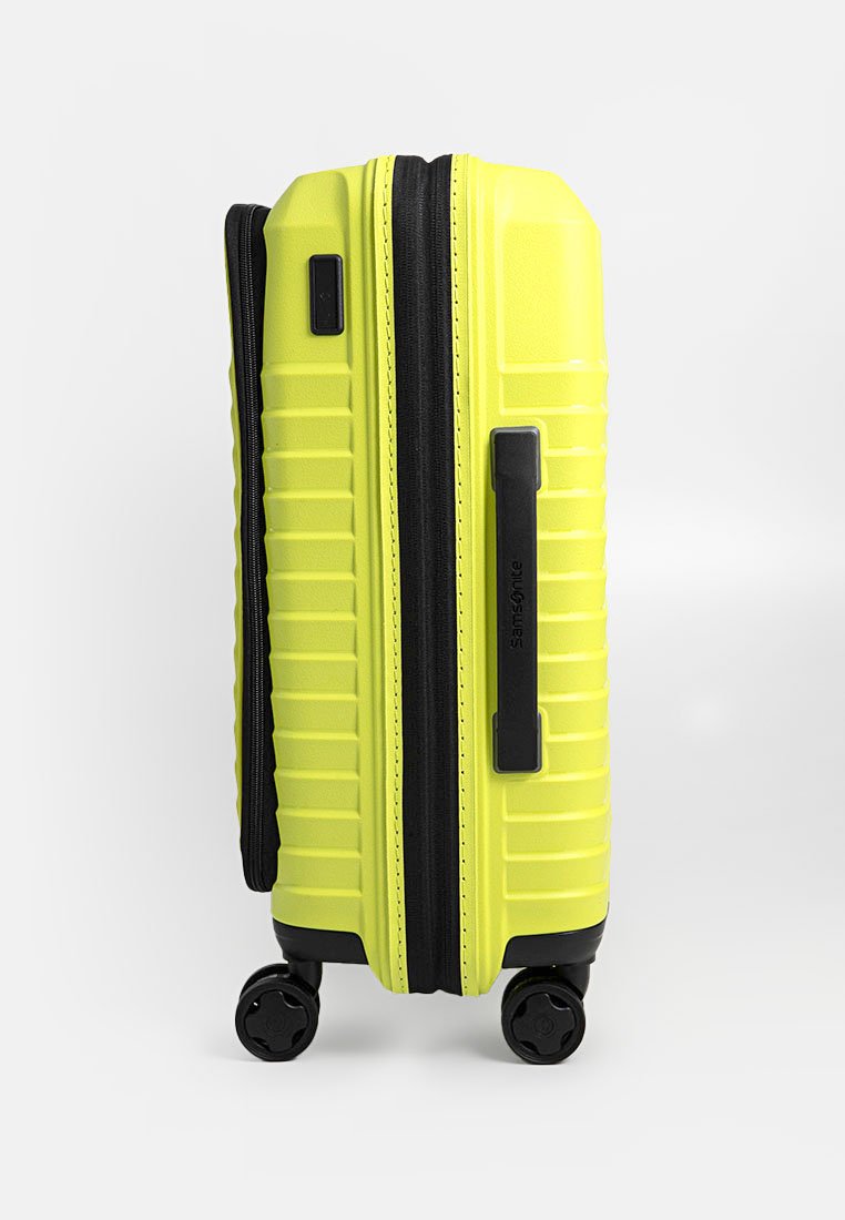 Maleta rígida de color amarillo brillante con textura estriada, cierre de cremallera, detalles en negro y cuatro ruedas giratorias para fácil movilidad.