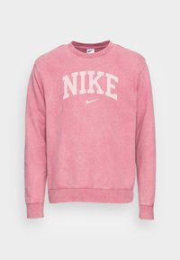 Rosa bomullströja med rund halsringning, långa ärmar och vit text "NIKE" fram, med en diskret sliten struktur.