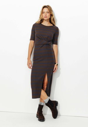 Robe midi rayée marron avec des manches courtes et une fente sur le côté, en matériau côtelé. Portez avec des bottines marron et des chaussettes grises.