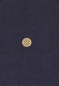 Navy gestrickter Pullover mit gerippter Textur und einem runden goldenen Emblem mit einem floralen Design auf der Vorderseite. Schlichte, strukturierte Oberfläche.