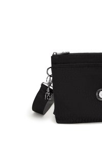 Borsa nera in nylon con design trapuntato, zip in argento, dettaglio con portachiavi e tracolla staccabile. Forma rettangolare compatta con tasca frontale.