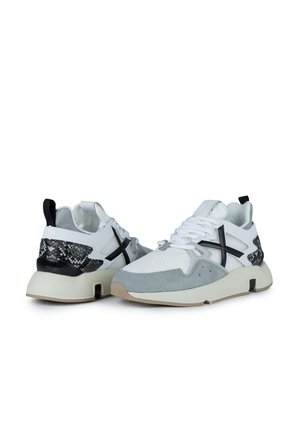 Sneakers sportivi con una tomaia in rete bianca, accenti in suede grigio, pelle di serpente nera sul tallone e una suola cremosa spessa.