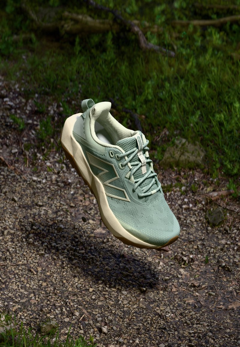 Light green athletic shoe with textured upper, lace-up design, and beige sole. Features subtle branding and a padded collar.