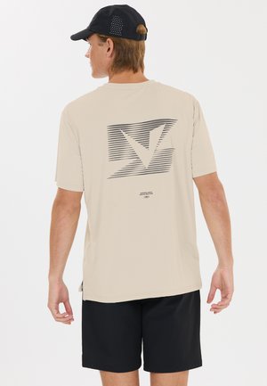 Homme portant un t-shirt graphique beige, un short noir et une casquette noire, vu de dos sur fond blanc uni.