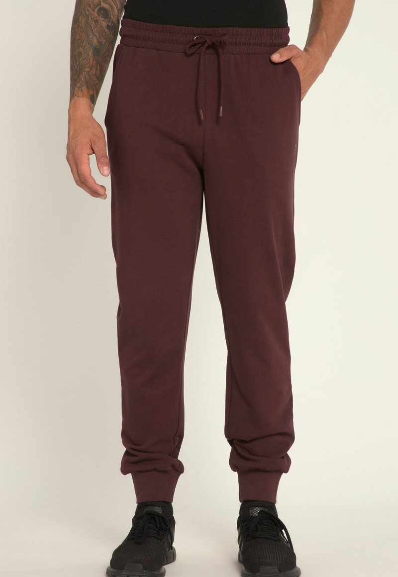 Burgundowe dresy z elastycznym pasem, zwężanym krojem, ściągaczami na nogawkach oraz kieszeniami. Wykonane z miękkiej, teksturowanej tkaniny.