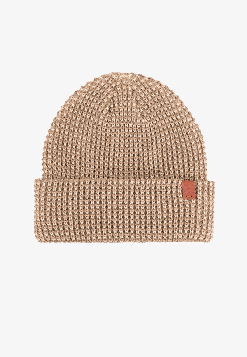 Czapka dzianinowa w jasnobeżowej wełnie, z wyraźnym wzorem i płaskim mankietem. Zawiera małą brązową skórzaną metkę po boku.