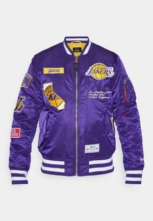 Paarse satin bomberjack met geborduurde patches, witte gestreepte manchetjes en een gele binnenvoering. Bevat een ritssluiting en zijzakken.