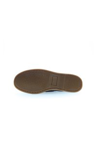 Schuhsohle aus strukturiertem braunem Gummi, mit einem rechteckigen Abschnitt nahe der Ferse und einem wellenförmigen Muster für besseren Halt.