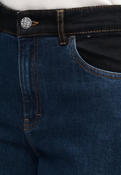 Τζιν παντελόνια σε σκούρο μπλε με πορτοκαλί ραφές, με κλείσιμο με μεταλλικό κουμπί και εμπρόσθιες τσέπες. Το ύφασμα έχει λεία υφή.