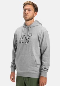 Sivá mikina s kapucňou a predným vreckom, s čiernym logom a dizajnom hviezdy. Dlhé rukávy s rebrovanými manžetami. Voľný strih.