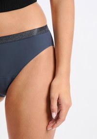 Ciemnoszary dół bikini z błyszczącym czarnym paskiem w talii. Gładka tekstura, minimalne pokrycie z wysokim wycięciem, charakteryzujące się czystymi liniami.