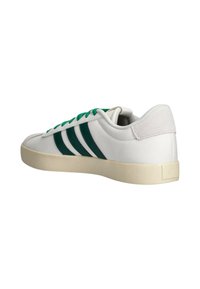 Zapatilla blanca con detalles verdes, con diseño de tres franjas, cordones planos, material de cuero texturizado y una suela de goma de color claro.