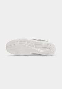 Semelle d'une basket grise et blanche montrant un motif détaillé de la bande de roulement avec des rainures et une prise texturée pour la traction.