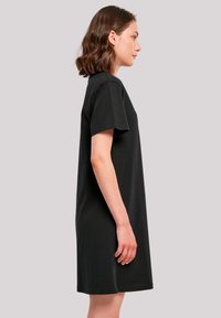 Schwarzes T-Shirt-Kleid mit kurzen Ärmeln aus Baumwolle, mit lockerer Passform und geradem Schnitt, das bis zur Mitte des Oberschenkels reicht.