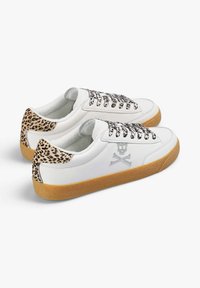 Zapatillas de cuero blancas con acentos de estampado de leopardo, suelas de goma y bordado de calavera y huesos cruzados en el lateral.