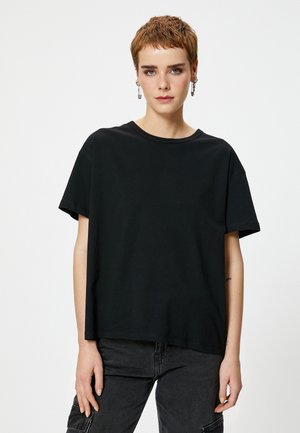 T-shirt in cotone nero con un fit rilassato, maniche corte e colletto a giro. Tessuto morbido; l'orlo arriva in vita. Adatto per un abbigliamento casual.