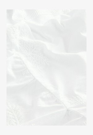 Bela tkanina z teksturirano vezenino v cvetličnem vzorcu, ki vključuje nežne gube in draperije ter poudarja gladek, lahek material.