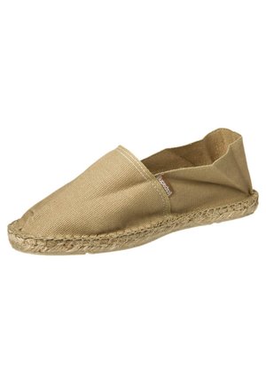 Beige canvas espadrille shoe with woven jute sole and small sewn-on brand tag on side, shown at an angle on white background.