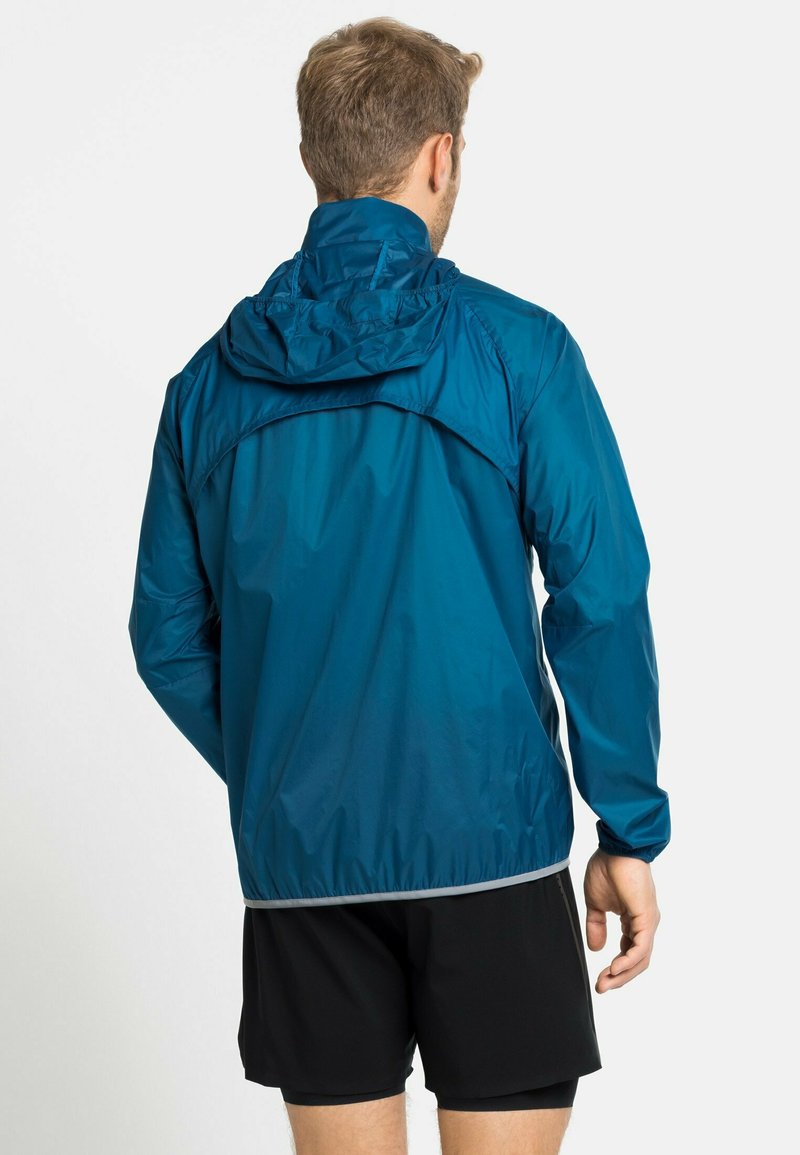 Wasserabweisende, kapuzenbejackte Jacke in Teal mit leichtem Design, elastischen Bündchen und reflektierenden Kanten entlang des Saums.
