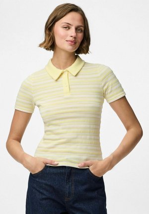 Polo de rayas amarillo claro con mangas cortas y un cuello suave. El material parece texturizado con un diseño ajustado. Combinado con pantalones de mezclilla oscuros.