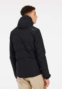 Schwarze isolierte Jacke mit Kapuze, ausgestattet mit einem Reißverschluss, gestepptem Muster und Logodetail an der Schulter. Glattes, leichtes Material.