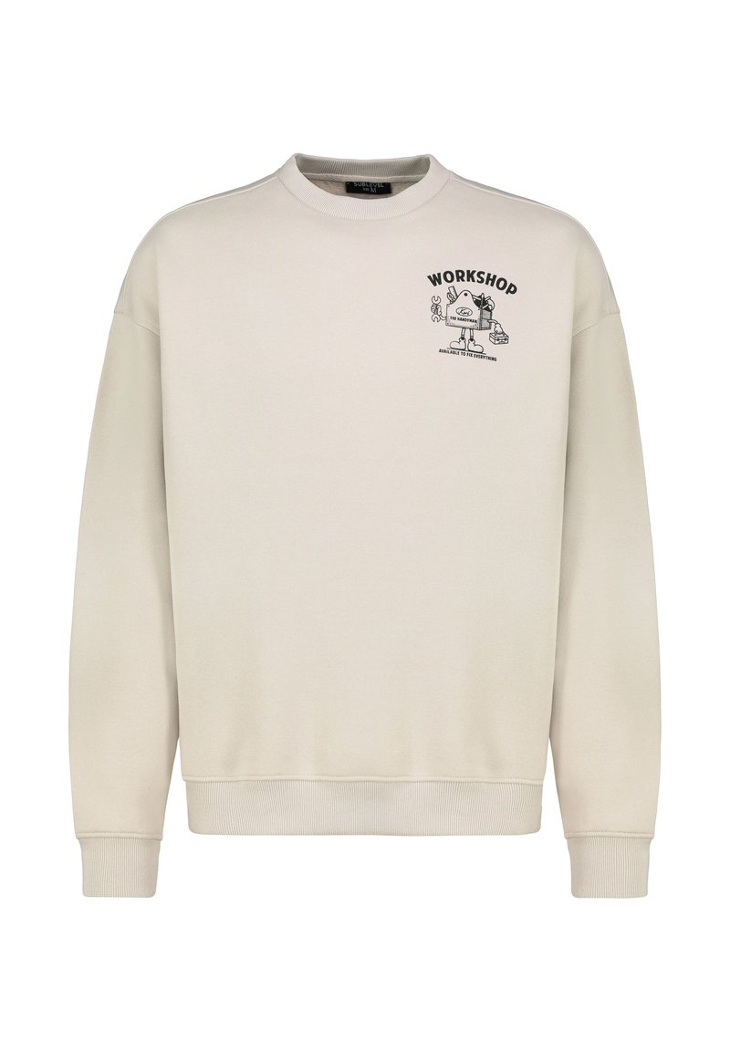 Light beige sweatshirt with a crew neck, ribbed cuffs, and hem. Features a black printed graphic with the text "WORKSHOP" on the chest.