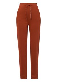 Joggers w kolorze rdzy, wykonane z miękkiego materiału, z elastycznym paskiem w talii z sznurkiem, zwężającymi się nogawkami oraz ściągaczami u dołu.