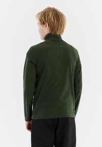 Zelený fleece pulóver s vysokým golierom, dlhými rukávmi a mäkkou textúrou. Obsahuje prešité lemovanie a malú logo nášivku na zadnej strane.